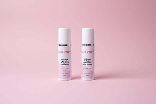 Two bottles of 'Bliss Forte' serum on a reflective surface with a purple background