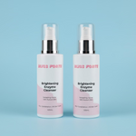 Two bottles of Bliss Forte Brightening Enzyme Cleanser on a green towel with a wooden background.