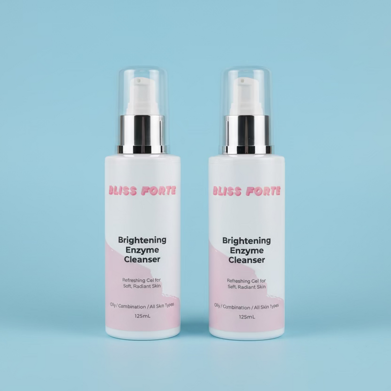 Two bottles of Bliss Forte Brightening Enzyme Cleanser on a green towel with a wooden background.