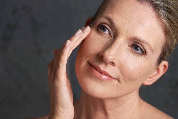 Woman applying moisturizer to her face, focusing on skin care to hydrate, nourish, and rejuvenate dry skin.